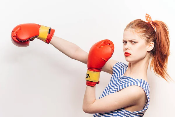 Une femme boxe sur un fond clair maquillage lumineux t-shirt rayé coiffure — Photo