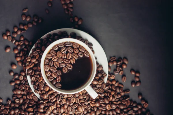 Ziarna kawy na szarym tle i gorący aromatyczny napój na spodzie widok z góry — Zdjęcie stockowe