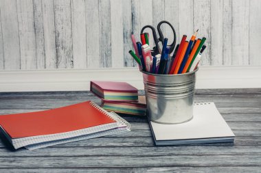 Demirden bir kavanozda kırtasiye malzemeleri ve ofisteki ahşap bir masada not defterleri.