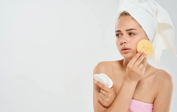 Žena s ručníkem na hlavě drží houbu v ruce kosmetologie dermatologie modelu — Stock fotografie