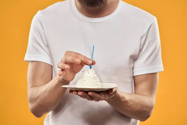 Un hombre con un pastel de cumpleaños en sus manos sobre un postre de cumpleaños de fondo amarillo — Foto de Stock