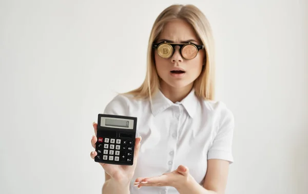 Loira em óculos com uma calculadora nas mãos de criptomoeda Bitcoin finanças — Fotografia de Stock
