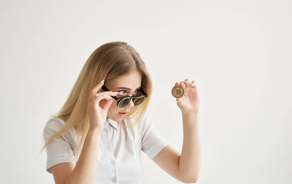 Деловая женщина в солнцезащитных очках держит в руках криптовалюту из золота биткойна — стоковое фото