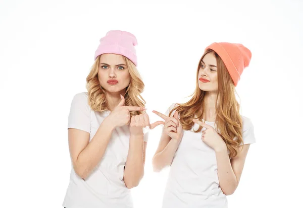 Dos hermanas en gorras multicolores se abrazan juntas Amistad comunicación entretenimiento moda —  Fotos de Stock