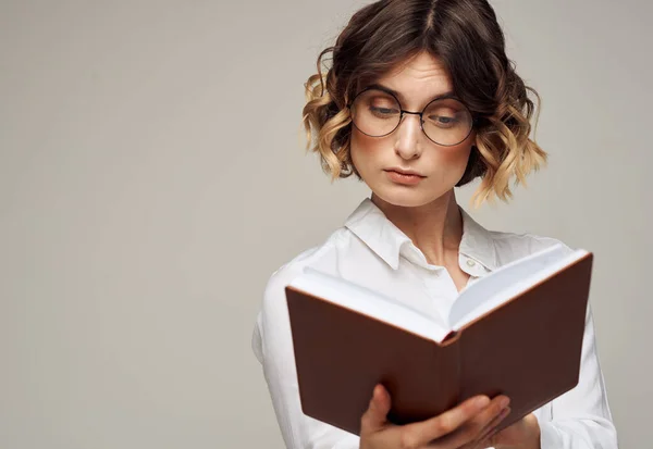 Femme intelligente avec un cahier dans les mains et dans une chemise blanche sur un fond gris vue recadrée — Photo