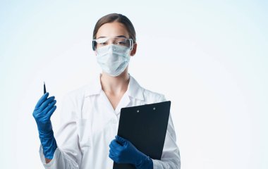 Tıbbi maskeli bir kadın laboratuvar asistanı. Şişede kimyasal bir madde var.