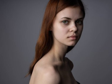 Çıplak omuzlu kızıl saçlı kadın. Yakın plan koyu renk arkaplan modeli.
