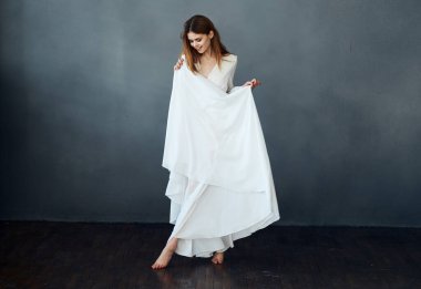 Beyaz elbiseli çekici bir kadının portresi. Gri bir arka planda. Tamamen büyümüş.