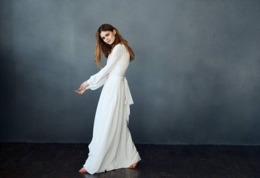 Beyaz elbiseli çekici bir kadının portresi. Gri bir arka planda. Tamamen büyümüş.