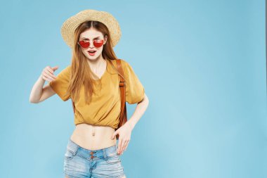 Şapkalı, güneş gözlüklü, sırt çantalı, güzel bir kadın.