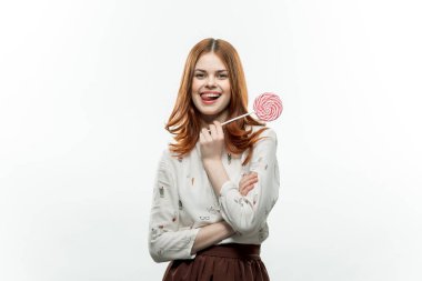 Dişlerinde lolipop tutan kadın arka planda hafif neşe