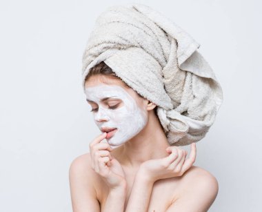 Çıplak omuzlu kadın kafasında krem havlu var.