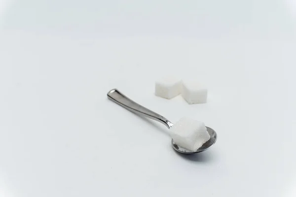 Cubes de sucre par cuillère à café de calories bonbons fond clair — Photo