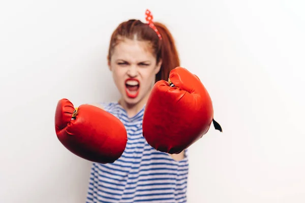 Agresszív sportos nő bokszkesztyűben és csíkos póló harcol könnyű háttérrel — Stock Fotó