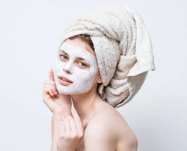 Wanita dengan krim di wajahnya handuk di perawatan kulit kepalanya — Stok Foto