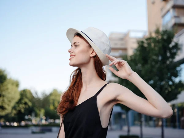 Bella donna in una maglietta nera e cappello stanno camminando per la strada vicino all'edificio — Foto Stock
