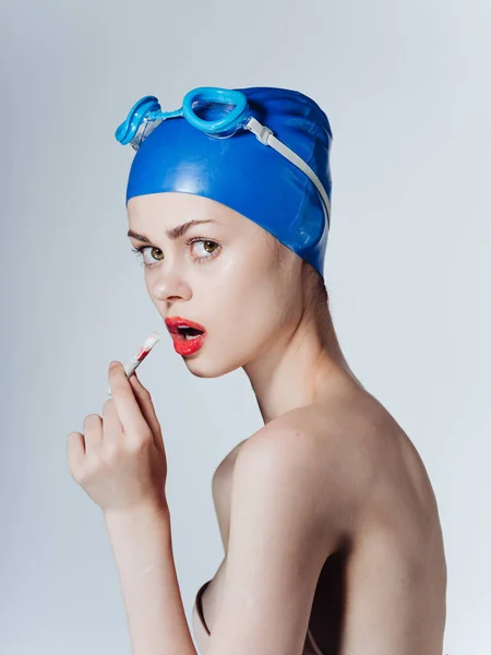 身穿蓝色泳帽的女子游泳者在浅色的背景下吸烟 — 图库照片
