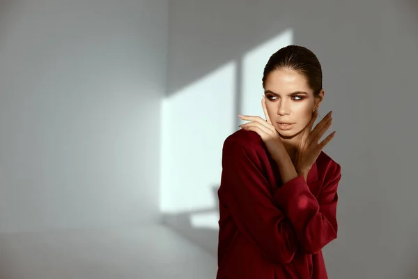 Mulher sexy em casaco vermelho olha para o lado e luz caindo da janela — Fotografia de Stock