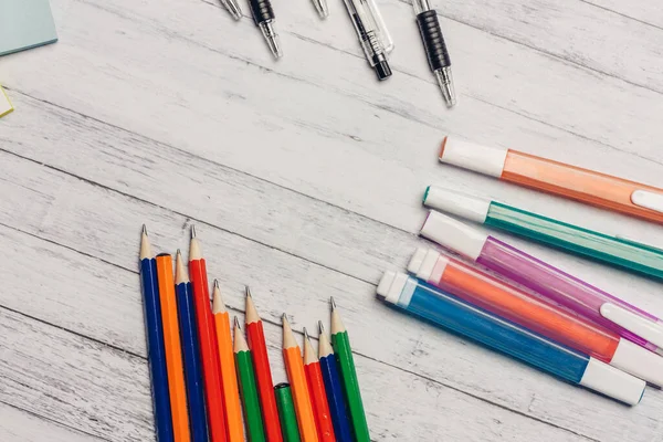 Rotuladores lápices bolígrafos sobre una mesa de madera y papel de oficina de colores — Foto de Stock
