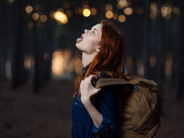 Mujer con una mochila y una camisa azul cerca de los árboles en el bosque modelo sonriente —  Fotos de Stock