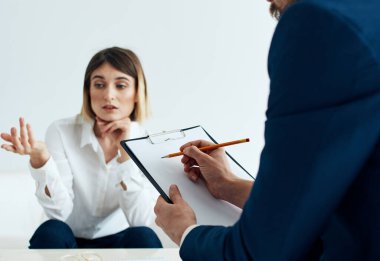 Elinde belgelerle klasik takım elbiseli bir adam ve koltukta duygusal bir kadın.