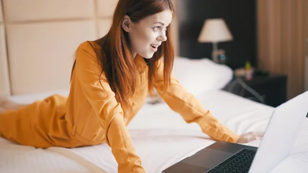 Vrolijke vrouw in de slaapkamer ligt op het bed voor de laptop communicatie — Stockfoto