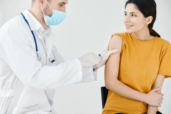 Un médico con una máscara médica y una bata sella una inyección en el hombro de una mujer con yeso adhesivo covid —  Fotos de Stock