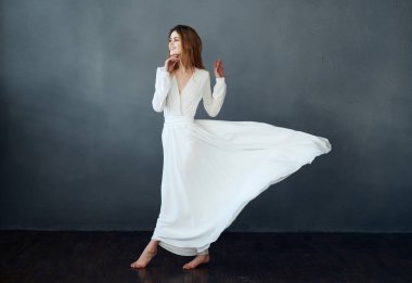 Beyaz elbiseli çekici bir kadının portresi. Gri bir arka planı var.