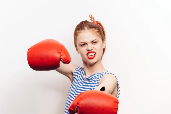 Mujer pelirroja en guantes se dedica al boxeo sobre un fondo claro modelo de agresión — Foto de Stock