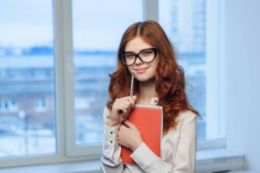 Elinde kırmızı bir not defteri olan bir finans yöneticisi olan iş kadını.