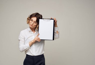 Gri arkaplandaki bir klasörde beyaz bir sayfa kağıdı olan kadın Boşluğu Kopyala