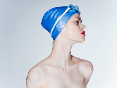 Açık arkaplanda bir kadın yüzücü portresi, çıplak omuzlar ve kırmızı dudaklar.