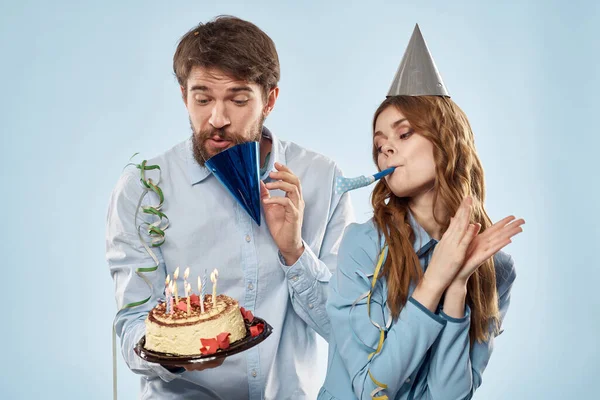 Homem de aniversário mulher em chapéus de festa em um fundo azul e bolo com velas — Fotografia de Stock