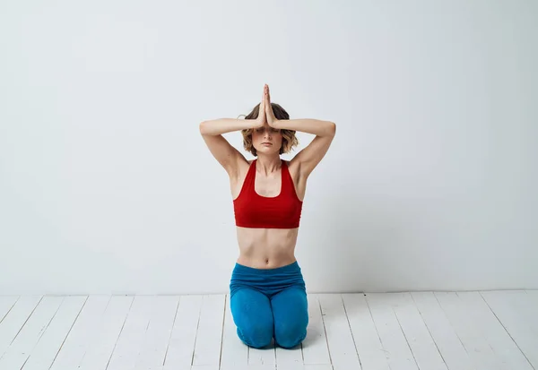 İnce bir kadın, yeni başlayanlar için yoga yapıyor. Gelişme çağında hafif bir arkaplan üzerine. — Stok fotoğraf