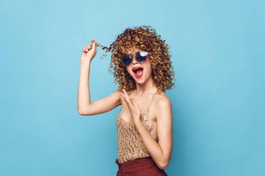 Güzel kadın kıvırcık saç duyguları mavi arkaplanı parlak makyajı cezbeder 