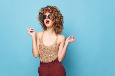 Çekici model kıvırcık saçlı, moda kıyafetleri kırmızı dudaklı, kırmızı pantolonlu. 