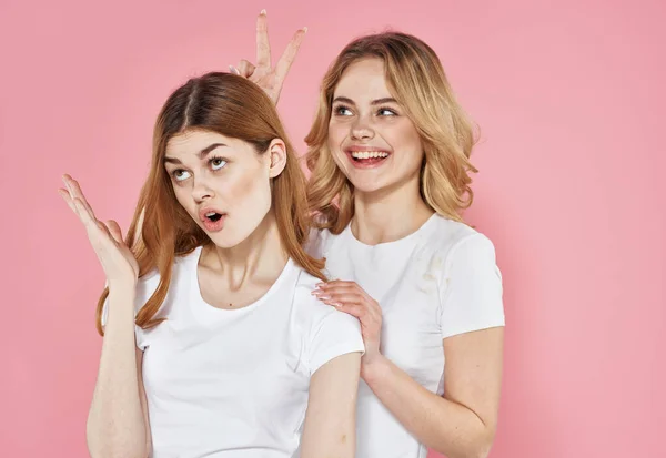 Két nő divat ruhák szórakoztató ölelés gondoskodó rózsaszín háttér — Stock Fotó