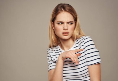 Tiksinti dolu sarışın kadın yana bakıyor ve bej arka plan kırpılmış.