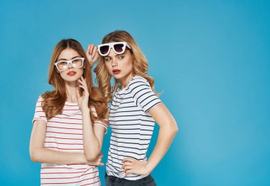 İki kız kardeş yan yana durur şık giyimli stüdyo lüks arkadaşlık masmavi arka plan