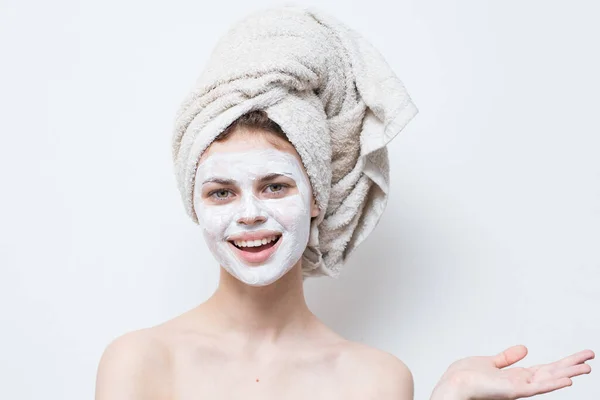 頭にタオルをかけ顔に保湿剤をかけた女性は — ストック写真
