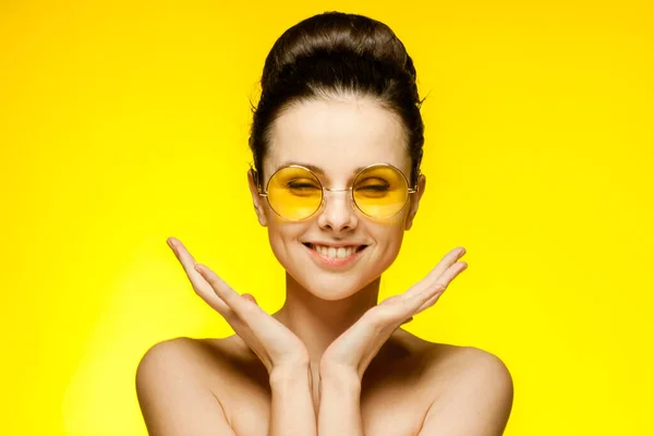 Wanita emosional dengan bahu telanjang memakai kacamata fashion mengumpulkan rambut latar belakang kuning — Stok Foto