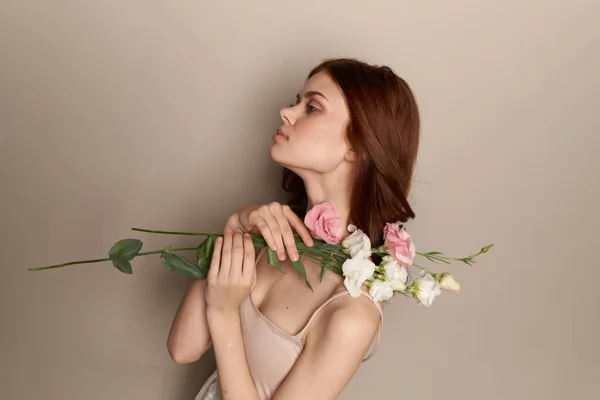 Szczęśliwa kobieta z bukietem lekkich kwiatów na beżowym tle nagie ramiona model rude włosy piękna twarz — Zdjęcie stockowe
