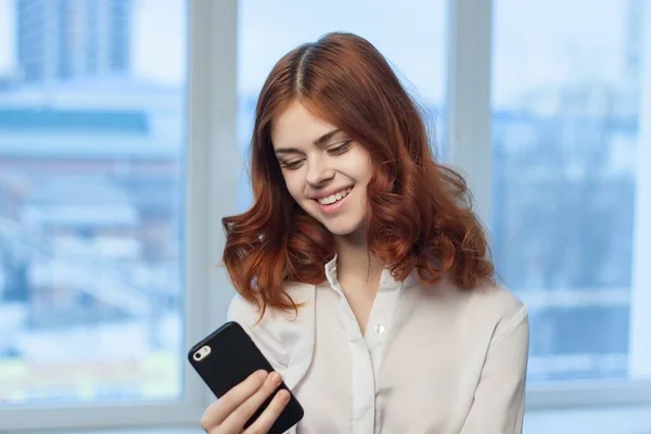 Frau im Hemd mit Handy in der Hand — Stockfoto