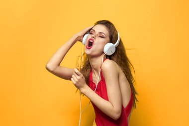 Kulaklıklı kadın müzik dinliyor. Duygular, yaşam tarzı, eğlenceli sarı arka plan.