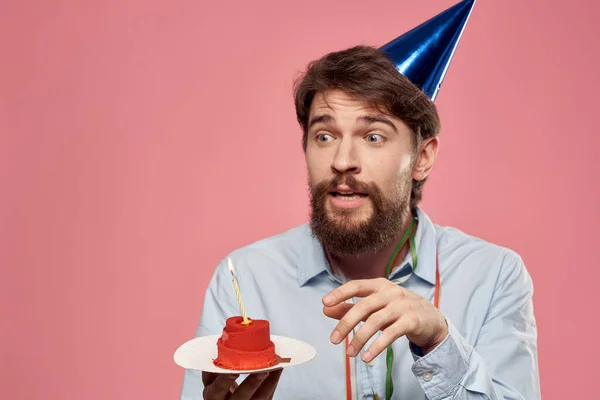 Cumpleaños de un hombre con un pastel y con una vela sobre un fondo rosa — Foto de Stock