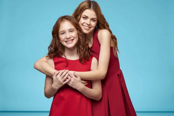Mutter und Tochter in roten Kleidern Unterhaltung Lifestyle Spaß Studio blauer Hintergrund — Stockfoto