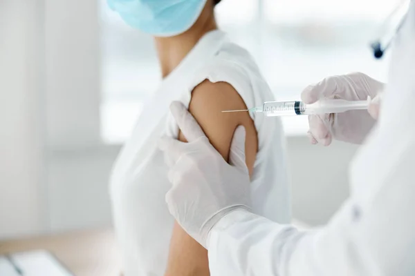 Kobieta w masce medycznej wykonująca szczepionkę przeciw koronawirusowi i lekarz ze strzykawką w ręku — Zdjęcie stockowe