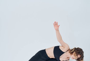 Hafif arka planda bir kadın egzersiz yapıyor. İnce bir yoga figürü.