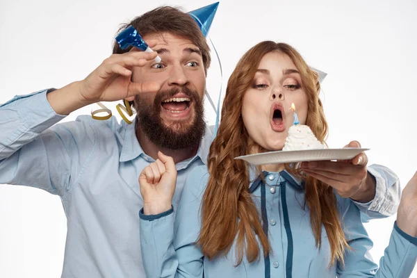 Homme et femme énergique avec un gâteau et chapeaux célébrer un anniversaire sur un fond clair — Photo