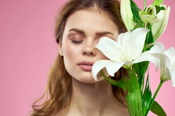 White flowers in female hands on a pink background portrait cropped view of model makeup